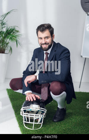 Smiling businessman with rugby helmet in office Banque D'Images