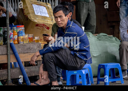 Hanoi, Vietnam - Mars 16, 2018 : l'homme assis sur une chaise en plastique dans un bar de la rue et 'bia hoi potable', la bière locale brassée de Hanoi Banque D'Images
