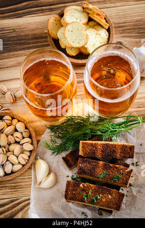 Deux verres de bière légère, les pistaches et les croûtons sur une table en bois. Vue d'en haut Banque D'Images