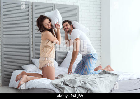 Jeune couple en pyjama body glamour sur le lit chez lui Banque D'Images