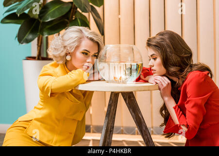 Portrait de jeunes femmes à la recherche de style rétro au poisson d'or dans l'aquarium, doll house concept Banque D'Images