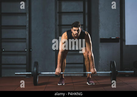 Vue avant du jeune sportsman préparer élever barbell dans sports hall Banque D'Images