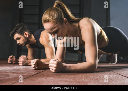 Les jeunes de la sportive et sportif faisant plank in gym Banque D'Images