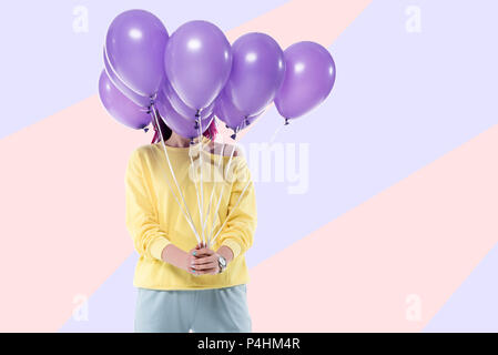 Woman covering face avec bouquet de ballons à l'hélium sur arrière-plan créatif Banque D'Images