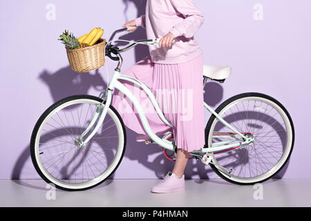 Cropped shot of woman in pink vêtements en location avec ananas et bananes dans panier Banque D'Images