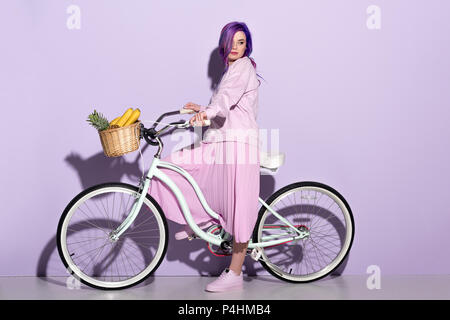 Vue latérale du jeune femme en rose vêtements sur location à l'ananas et bananes dans panier Banque D'Images