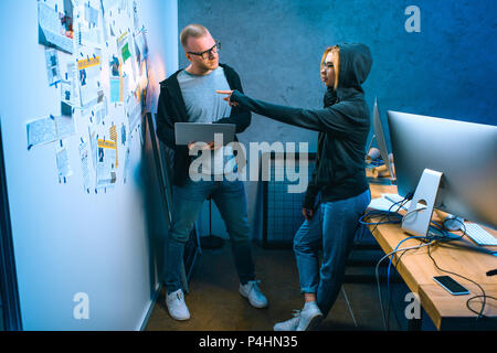 Couple de pirates informatiques travaillant sur les logiciels malveillants ensemble in dark room Banque D'Images