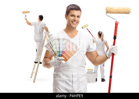 Painter holding un échantillon de couleur et un rouleau à peindre avec deux peintres peinture derrière lui isolé sur fond blanc Banque D'Images