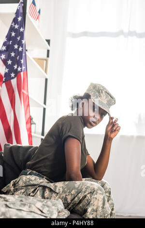 Jeune femme soldat en vêtements de camouflage sitting on sofa Banque D'Images