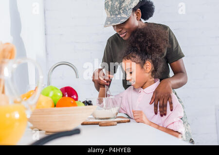 Soldat américain africain avec petite fille ensemble à la maison cuisine équipée Banque D'Images