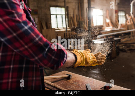 Cropped shot d'artisan en secouant des gants de plaquettes de bois déchets de scierie à mains Banque D'Images