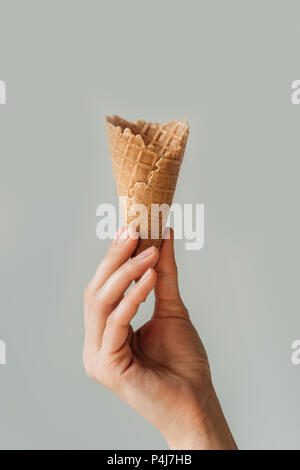 Portrait of woman holding empty waffle cornet de crème glacée à la main isolé sur gray Banque D'Images