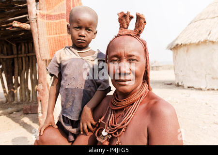 Femme Himba avec son petit fils souriant pour l'appareil photo dans le village de peuple Himba Banque D'Images