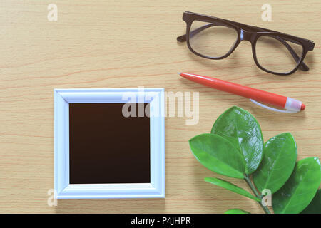 Cadre photo vintage et spectacles près de stylo rouge placé sur un plancher en bois brun et avoir l'espace pour copier dans votre travail de conception concept. Banque D'Images