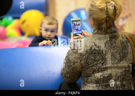 Biélorussie, Minsk, le 10 mars 2018. Maison de vacances d'enfants à l'ouverture du magasin Caravan.grand-mère prend une photo de son petit-fils sur son mobile ph Banque D'Images