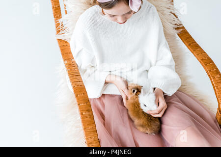 High angle view of Girl with cute bunnies furry assis dans un rocking-chair Banque D'Images