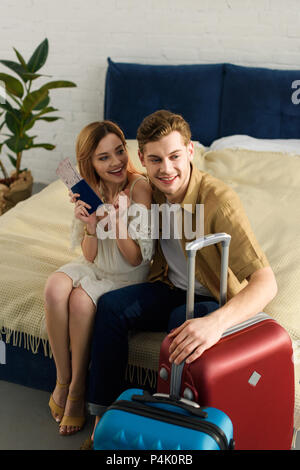 Jeune couple avec des valises prêtes pour locations assis sur le lit et de nationalités Banque D'Images