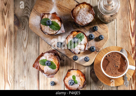 Muffins aux myrtilles et une tasse de chocolat chaud sur un fond de bois à pâte fait maison.. Vue d'en haut Banque D'Images