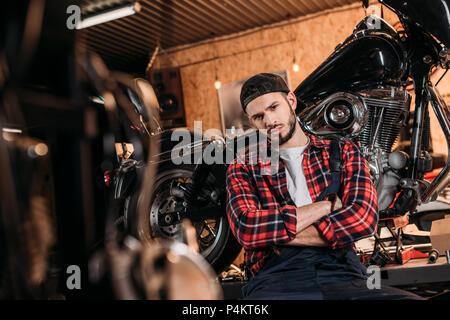 Beau bike repair station worker sitting in front of motorcycle Banque D'Images