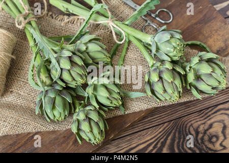 Deux bouquets d'artichauts sur table de cuisine parmi certains éléments de cuisine Banque D'Images