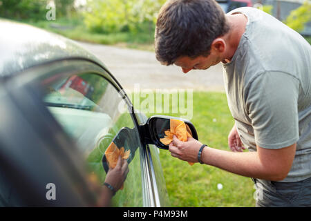 Voiture d'essuyage- Jeune homme voiture nettoyage avec chiffon en microfibre, esthétique auto Banque D'Images