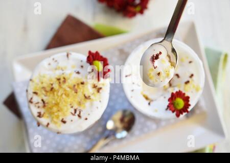 Le chocolat, les céréales et le lait de coco en dessert deux verres décorés de fleurs fraîches (vu du dessus) Banque D'Images