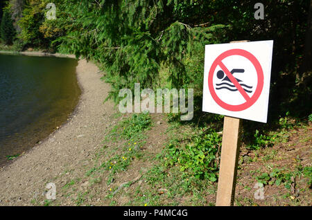 Un pilier avec un signe indiquant une interdiction de baignade. Le signe montre une personne flottant barrée . Banque D'Images