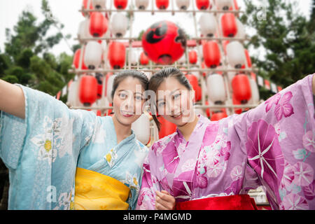 Deux jeunes femmes asiatiques tenant la main et ouvrit les bras pour prendre une photo en face de lots lanterne rouge et blanc. Banque D'Images