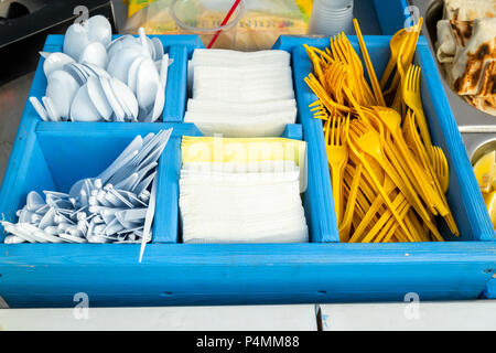 Fourchettes et cuillères jetables en plastique avec des serviettes dans une boîte en bois bleu Banque D'Images