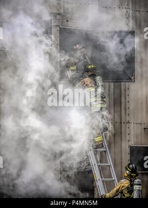 Les pompiers en descendant une échelle de sauvetage à un centre de formation. Banque D'Images