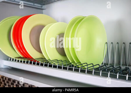 Un ensemble de plats multi-couleurs est séché et stocké sur un support métallique. Banque D'Images