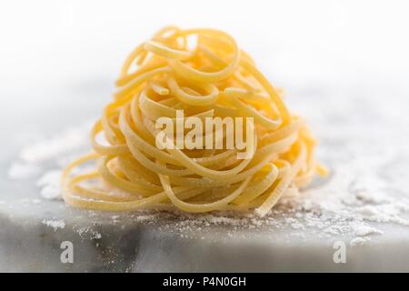 Nid de linguine fraîches sur une surface en marbre fariné Banque D'Images