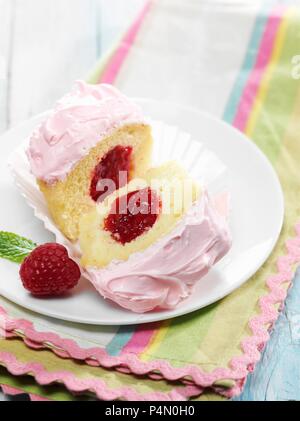 Cupcake à la vanille Confiture de framboises avec du glaçage rose et centre Banque D'Images