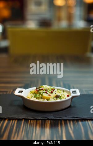 Salade de pommes de terre et de poivre et les câpres dans un bol sur une table dans un restaurant. Banque D'Images