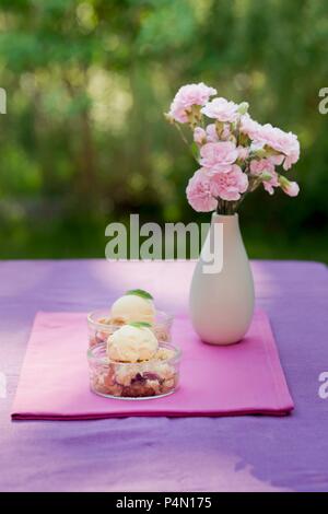Crumble aux fraises avec glace à la vanille en dessert plats sur une table de jardin Banque D'Images
