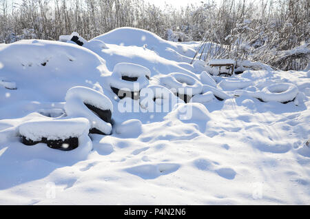 Utilisées et rejetées les pneus de voiture se trouvent sur le côté de la route, couvert d'une épaisse couche de neige . Banque D'Images