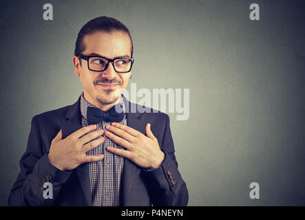 Jeune homme fou dans les verres et de costume à la main dans la main à nerdy sur la poitrine de la timidité sur fond gris Banque D'Images