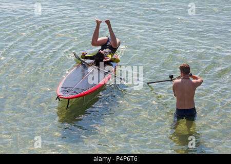 Bournemouth, Dorset, UK. 23 juin 2018. Météo France : belle matinée ensoleillée à chaud des plages de Bournemouth en tant que visiteurs, chef de la station tôt pour obtenir un espace avant qu'il soit emballé plus tard et à profiter du soleil à la hausse des températures pour la canicule. Les amis s'amusant rester au frais sur leurs paddleboards dans la mer. La capture de l'instant ! Femme en paddleboard paddle board. Credit : Carolyn Jenkins/Alamy Live News Banque D'Images