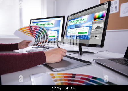 Vue latérale d'un jeune designer Holding Swatch colorés working on Computer in Office Banque D'Images