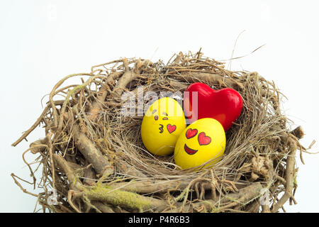 Deux oeufs de Pâques peints avec des émoticônes, un dans l'amour et d'autres baisers, placé dans une niche en isolé sur fond blanc. Banque D'Images