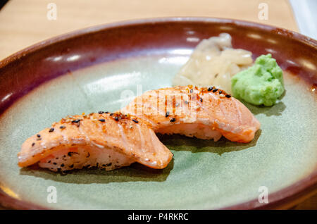 Délicatesse japonaise nigiri saumon grillé avec sushi wasabi vert et gingembre mariné sur la plaque Banque D'Images