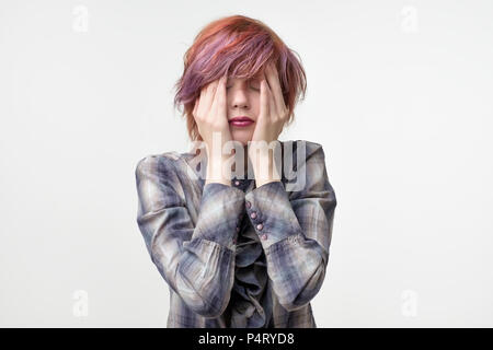 Portrait de femme assez informel inhabituelles avec des hairstyle ayant terrible mal de tête. Doivent faire face en essayant de frotter un peu la douleur. Banque D'Images