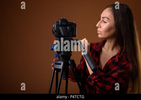 Studio shot of young Beautiful woman vlogging contre brown retour Banque D'Images