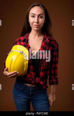 Jeune femme belle construction worker contre brown backgrou Banque D'Images