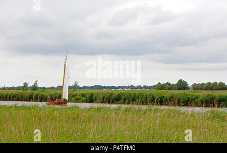 Un petit yacht naviguant sur la rivière Bure sur un jour nuageux et venteux sur les Norfolk Broads à Upton, Norfolk, Angleterre, Royaume-Uni, Europe. Banque D'Images