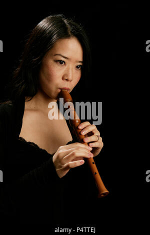 Jeune femme jouant de la flûte soprano recorder ou Banque D'Images