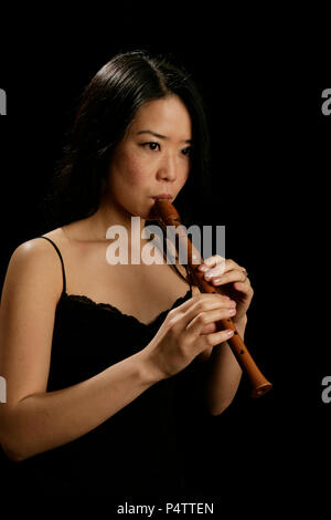 Jeune femme jouant de la flûte soprano recorder ou Banque D'Images