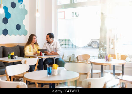 Jeune femme et l'homme partager comprimé dans un cafe Banque D'Images