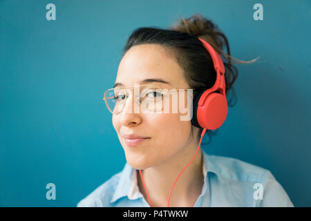 Portrait de femme souriant à l'écoute de la musique avec des écouteurs Banque D'Images