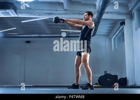 Athletic man doing kettlebell exercice swing at gym Banque D'Images